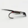 Close-up of an artificial fishing fly with a curved hook, brown segmented body, black hackle fibers, and a small red thread near the head.