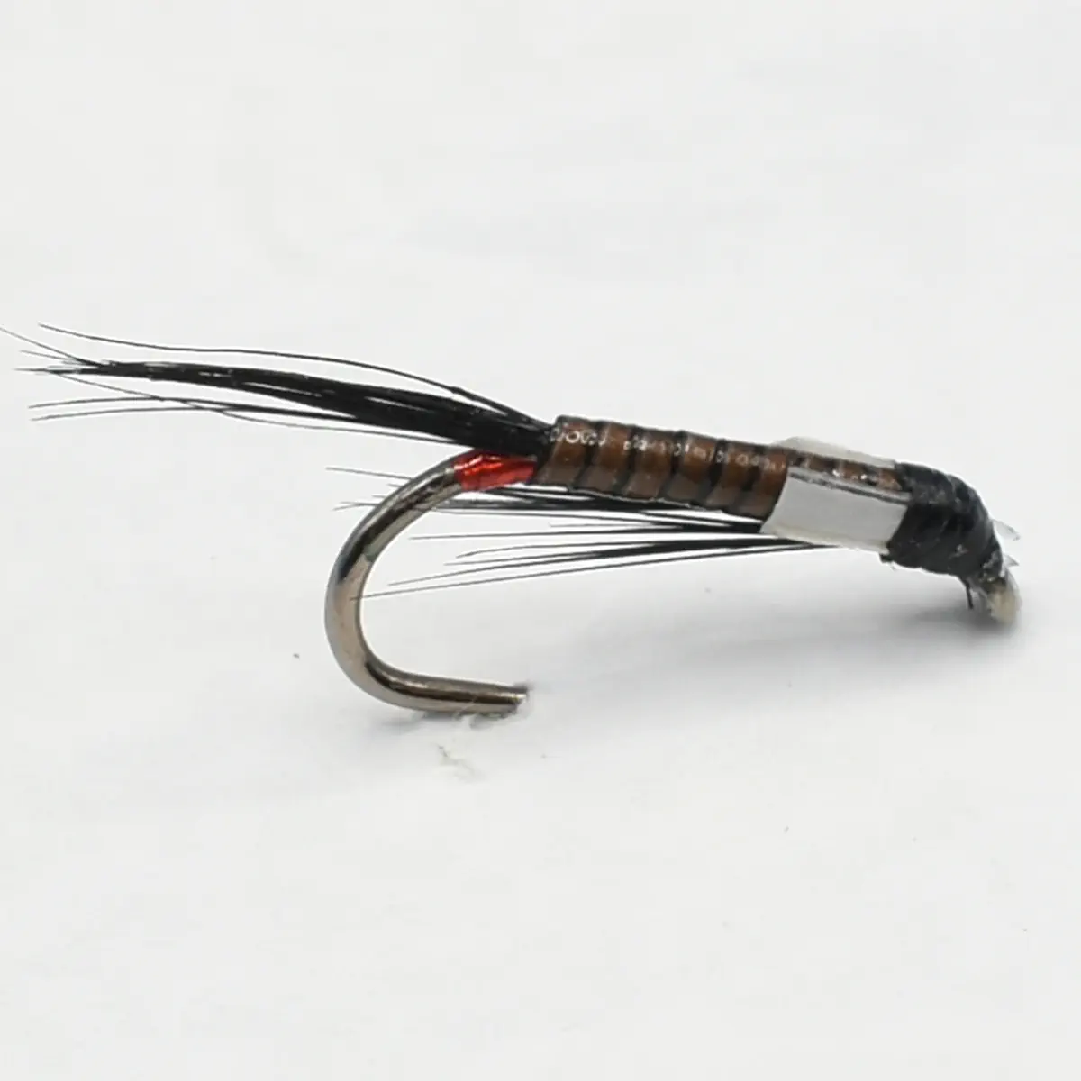 Close-up of an artificial fishing fly with a curved hook, brown segmented body, black hackle fibers, and a small red thread near the head.