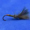 Close-up of a fly fishing lure: a black curved hook with a striped yellow-brown body and dark brown feather tail on a blue surface.