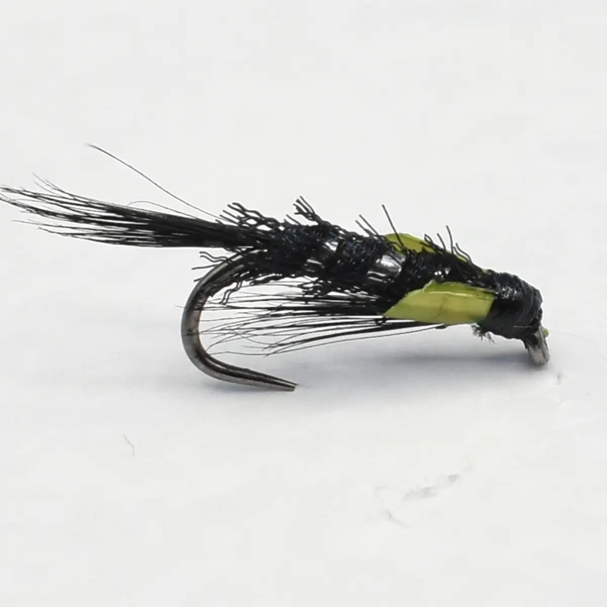 Close-up of a black-and-olive fishing fly tied with feather-like strands for trout fishing.