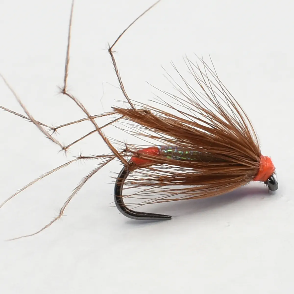 Brown dry fly fishing lure with long hackle and orange head mounted on a curved hook