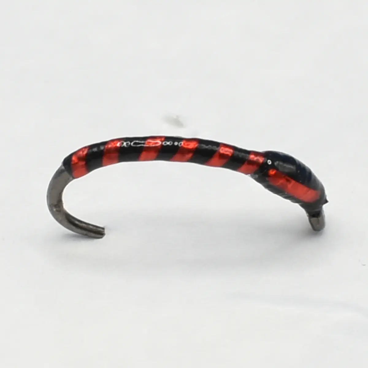 Curved bracelet with alternating red and black stripes on a light background.