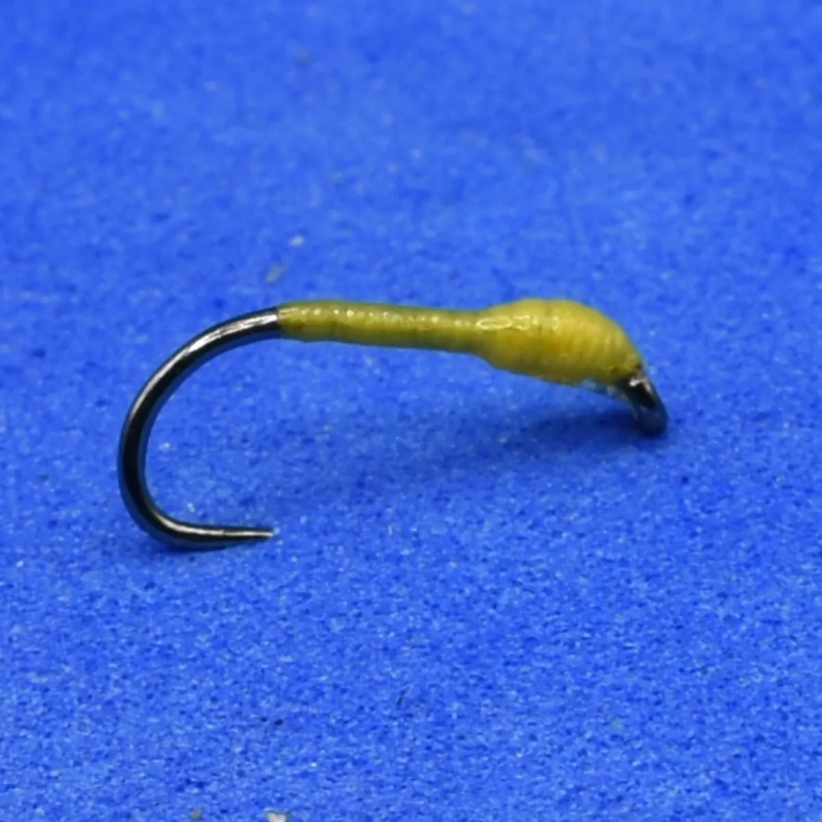 Small fishing hook with a yellow soft plastic worm lure attached, ready for fishing