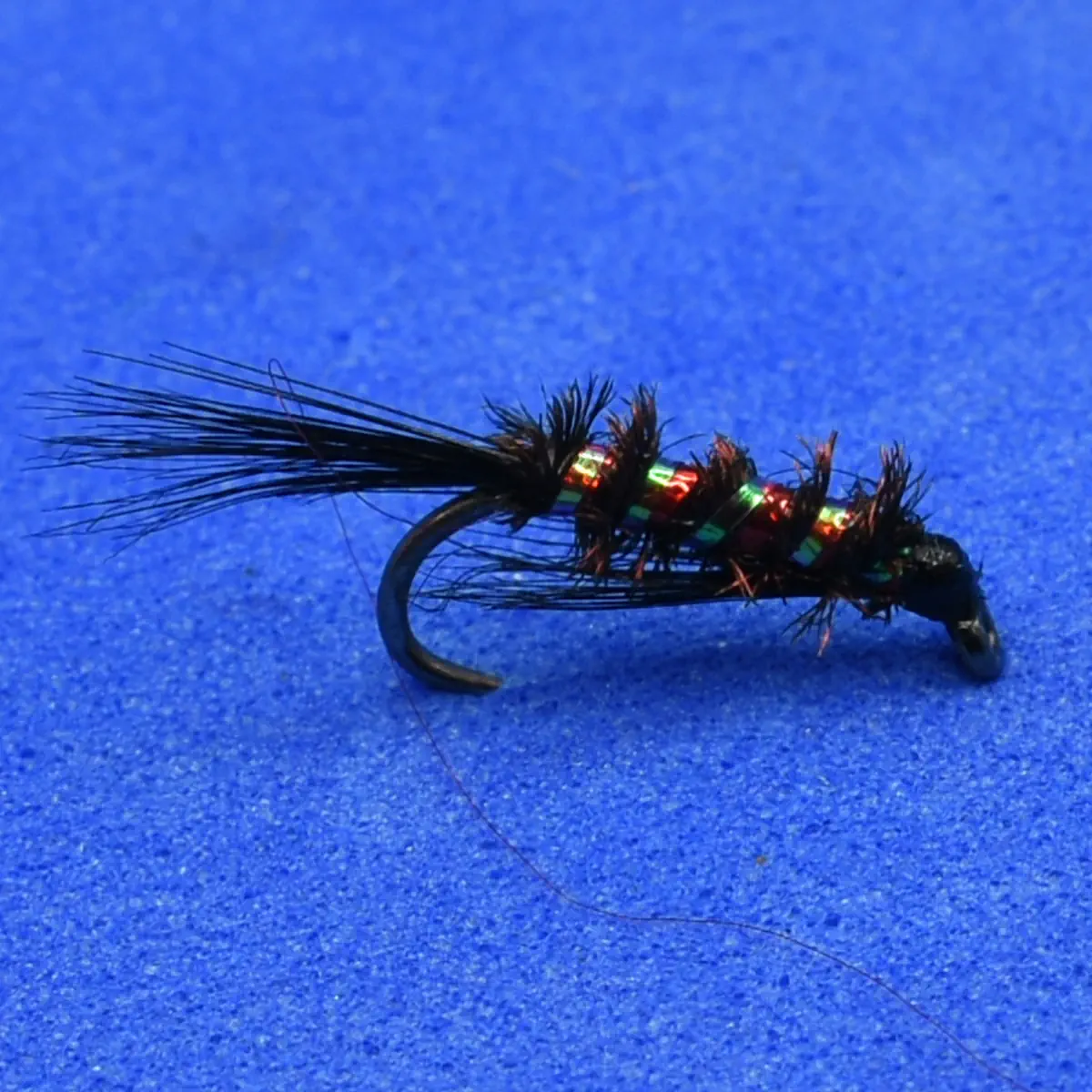 Artificial fishing fly with black hackle and iridescent bead-head, mounted on a curved hook.