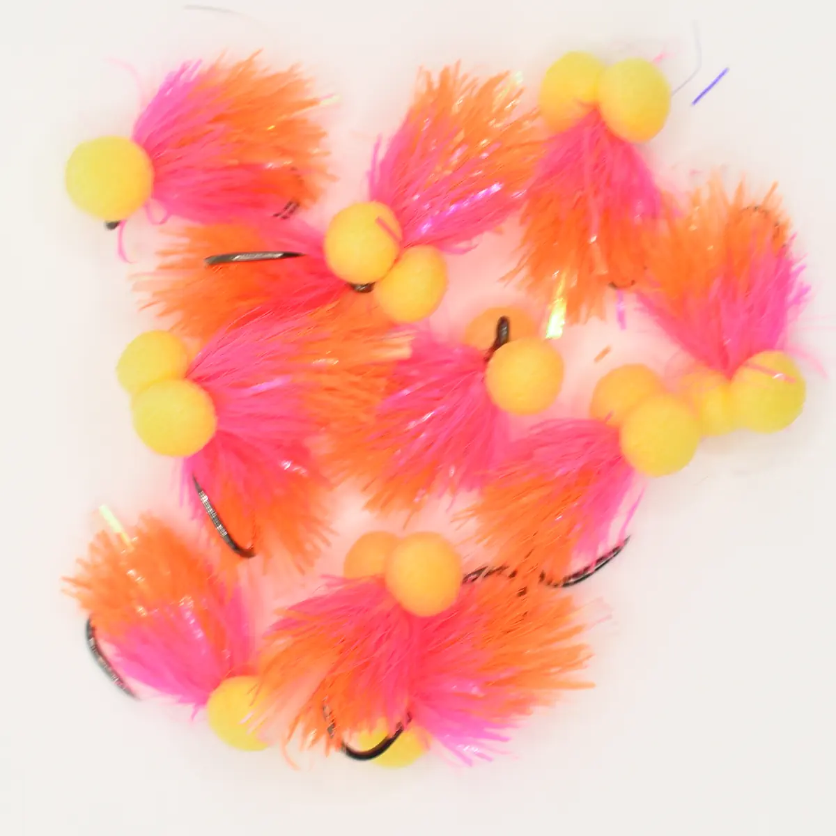 Assorted bright pink and orange marabou fishing lures with yellow foam bobbers and visible hooks laid on a white background.