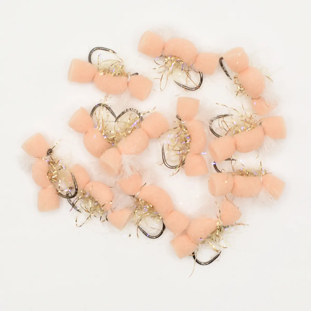 Cluster of pink fluffy fishing lures with gold tinsel and hooks on a white background.