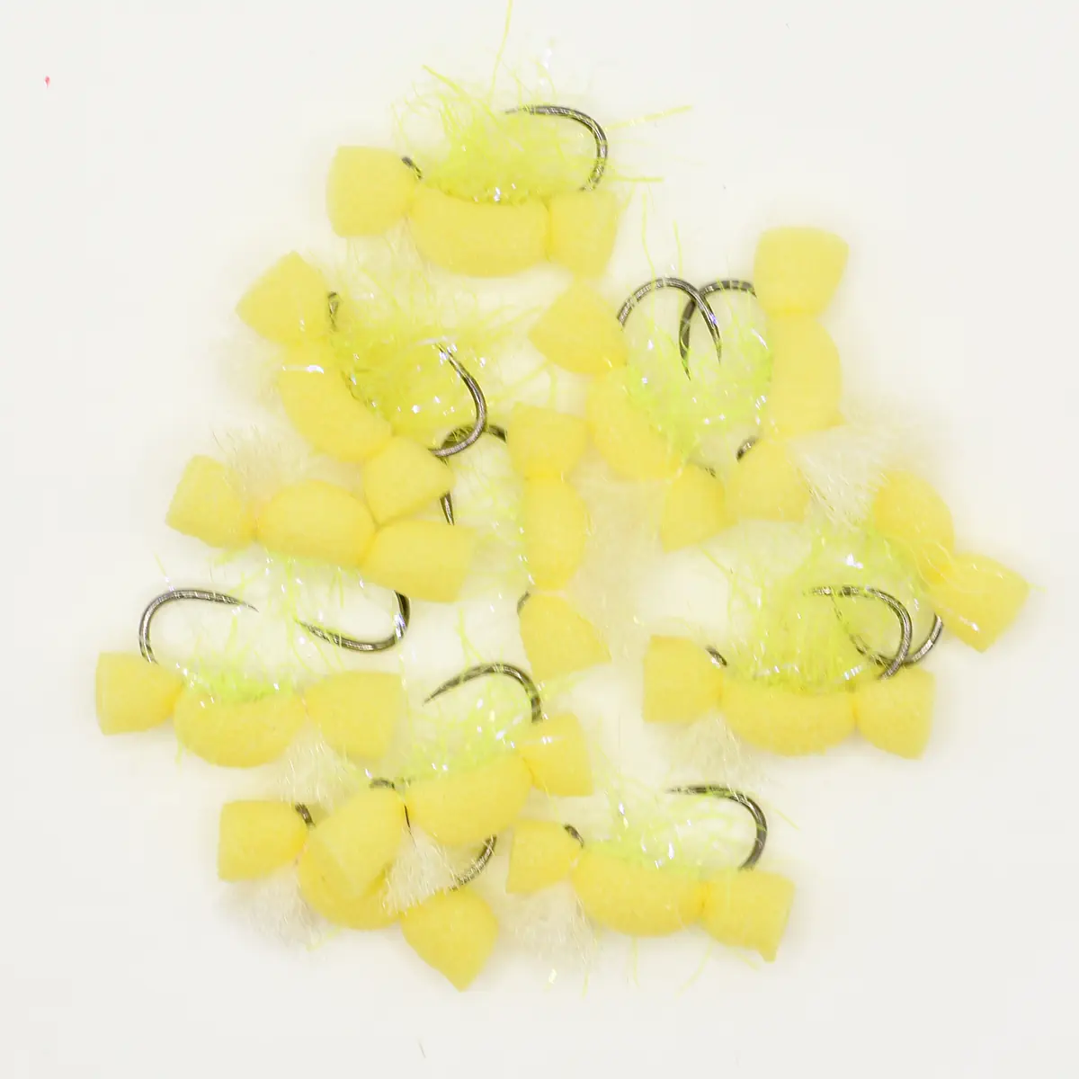 Pile of yellow foam fishing flies with white feather accents and metal hooks
