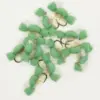 Assorted green foam fishing lures with hooks and iridescent strands laid in a pile.
