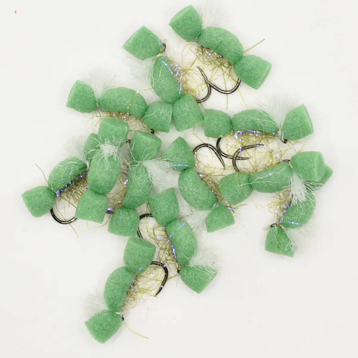 Assorted green foam fishing lures with hooks and iridescent strands laid in a pile.