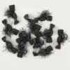 Assorted black foam fishing lures with purple tinsel and white fluffy fibers on a white background.