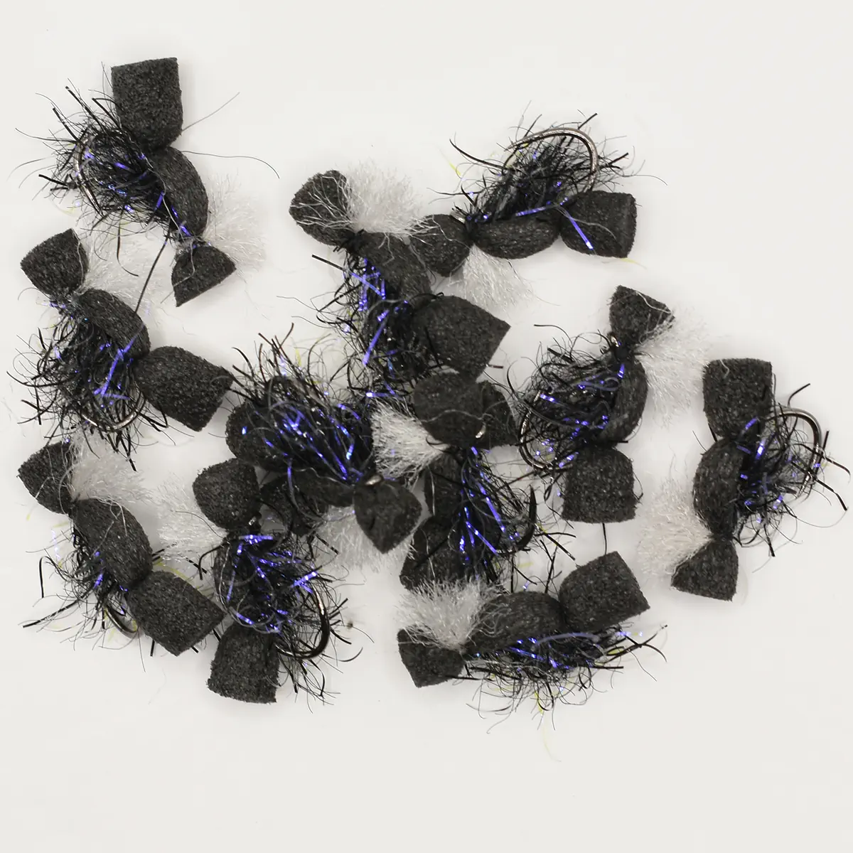 Assorted black foam fishing lures with purple tinsel and white fluffy fibers on a white background.