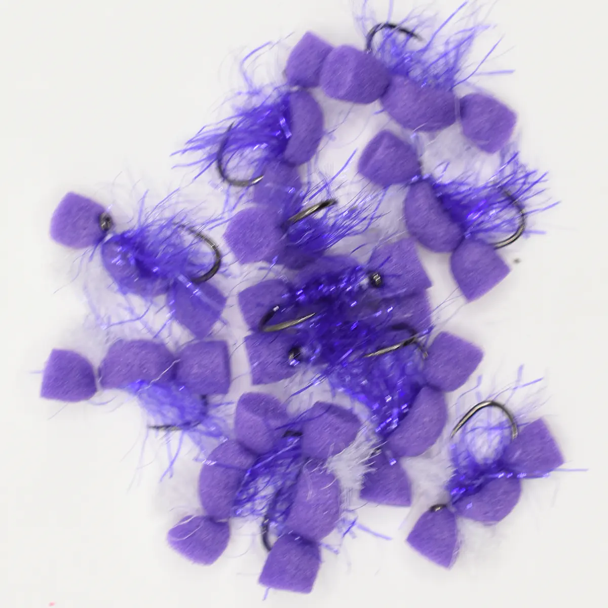 Several purple fuzzy pom-pom fishing lures with hooks on a white surface.