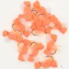 Assortment of orange foam-bodied fishing lures with curved hooks and wispy tails on a white background.