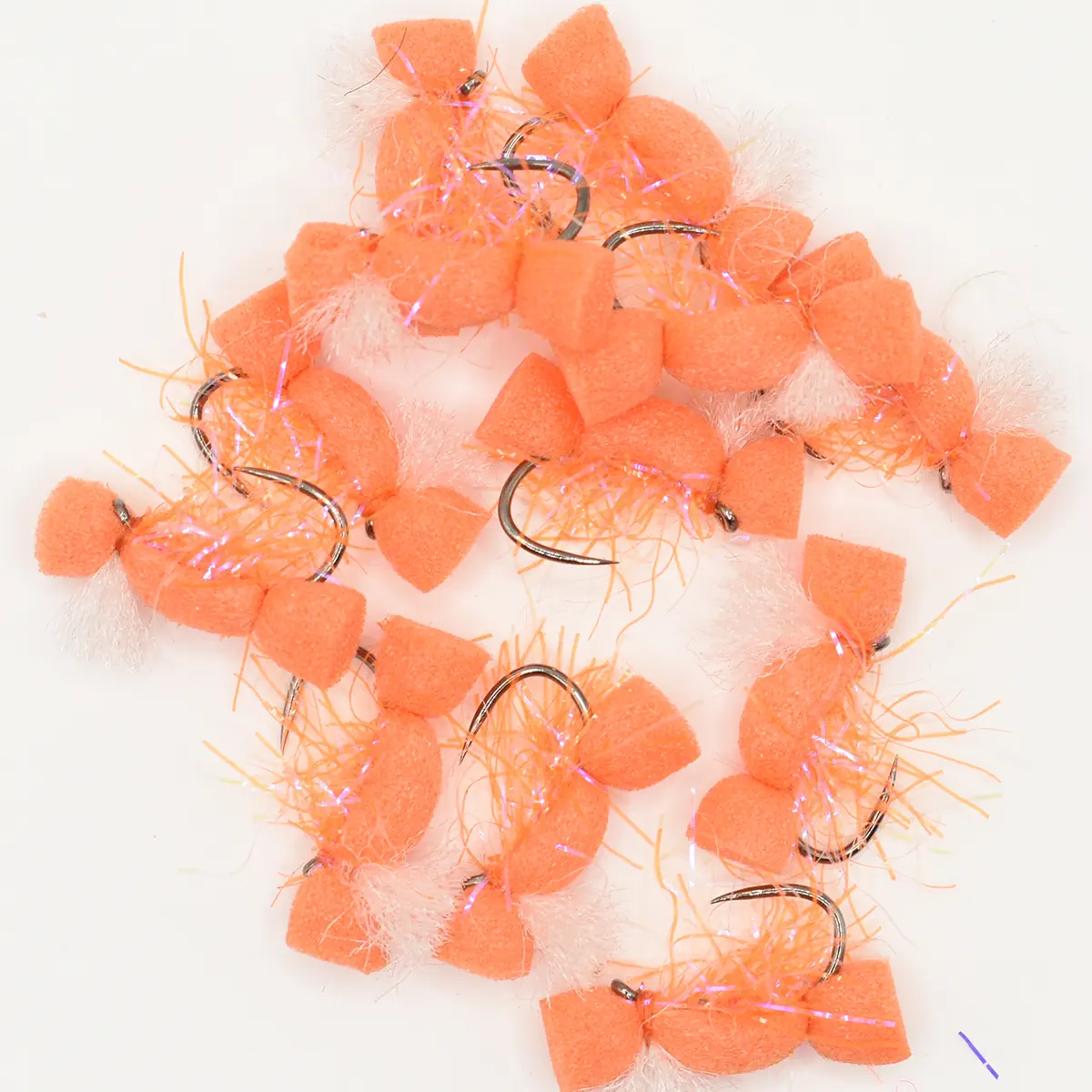 Assortment of orange foam-bodied fishing lures with curved hooks and wispy tails on a white background.