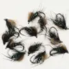 Assorted black-and-brown fly fishing lures with green bead eyes laid out on a white surface