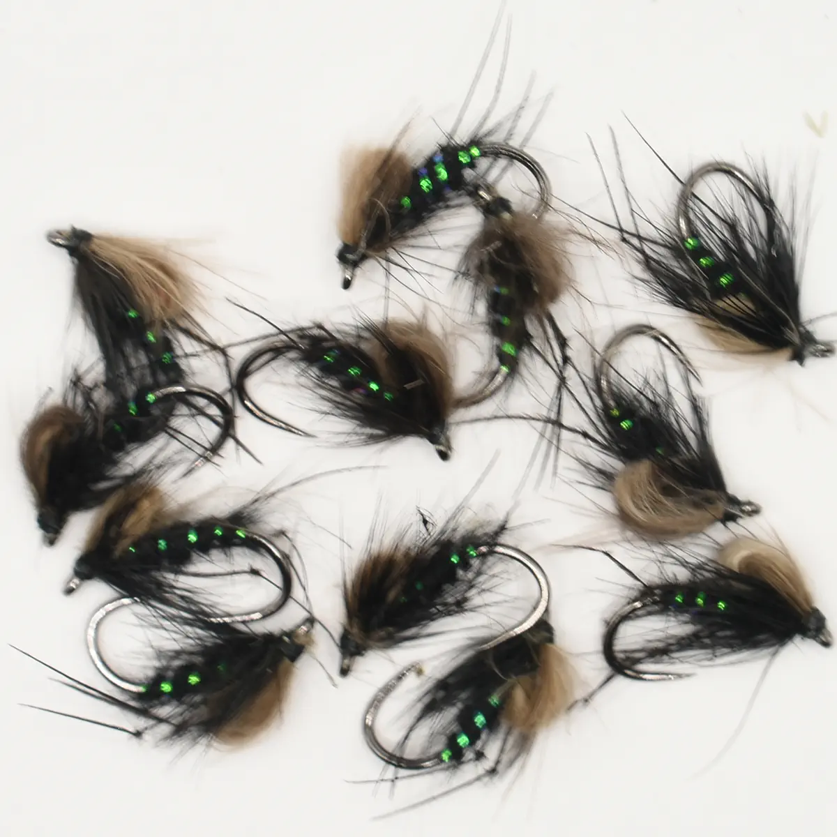 Assorted black-and-brown fly fishing lures with green bead eyes laid out on a white surface