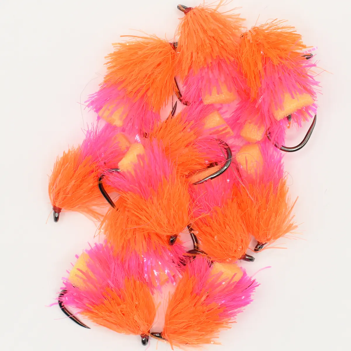 Assorted bright orange and pink marabou feather fishing lures with hooks on a white background