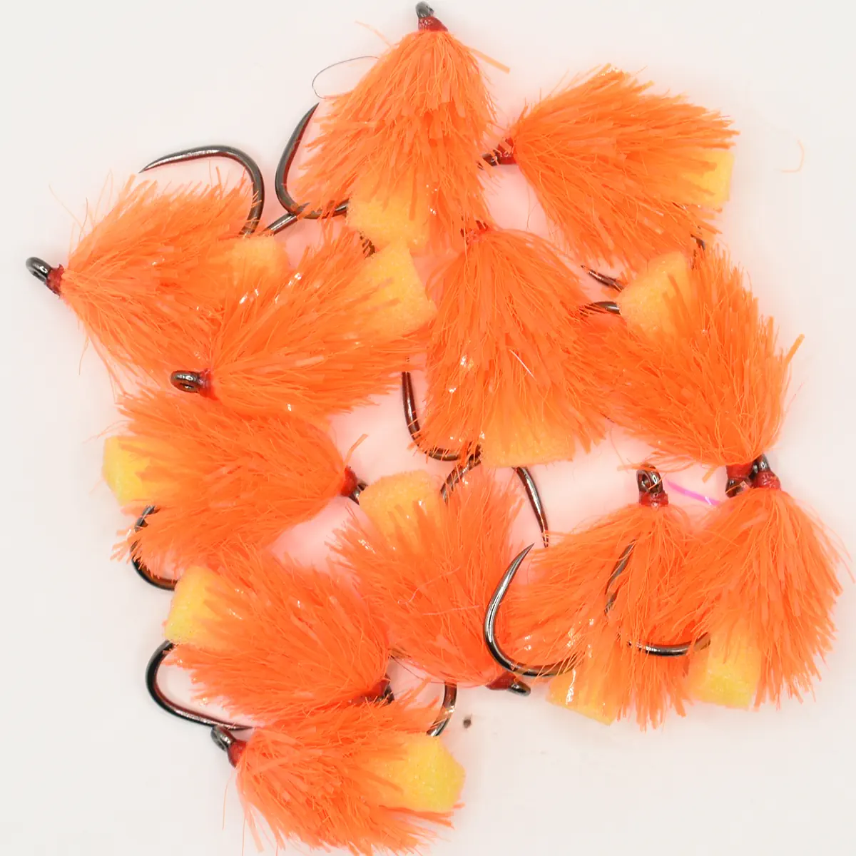 Assorted bright orange fishing flies with fluffy material and hooks for fly fishing (on white background)