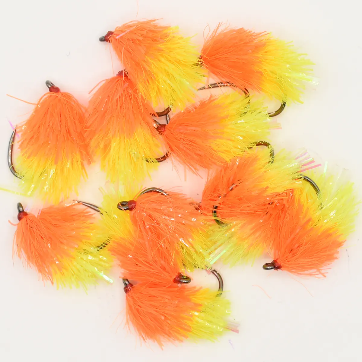 Bright orange and yellow fuzzy fishing lures with hooks arranged together, used as bait for fishing.