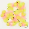 Assortment of pink and yellow fishing flies with fuzzy tails and hooks on a white background.