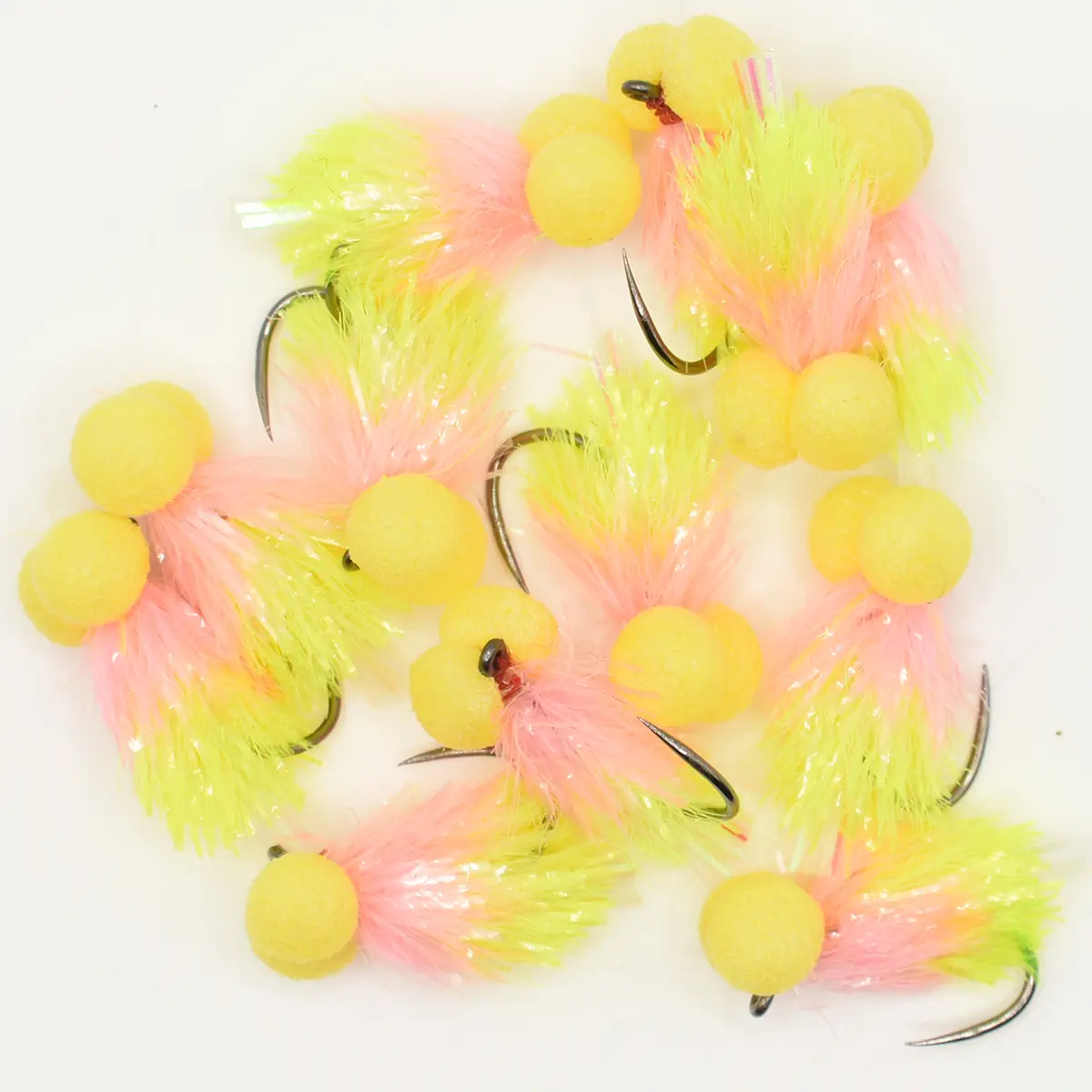 Assortment of pink and yellow fishing flies with fuzzy tails and hooks on a white background.