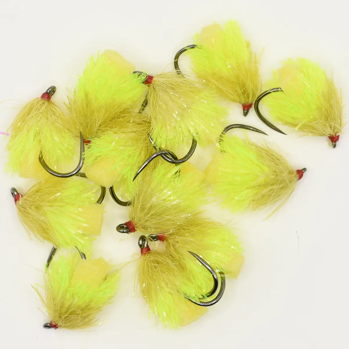 Bright yellow fly fishing lures with red heads on metal hooks, piled together