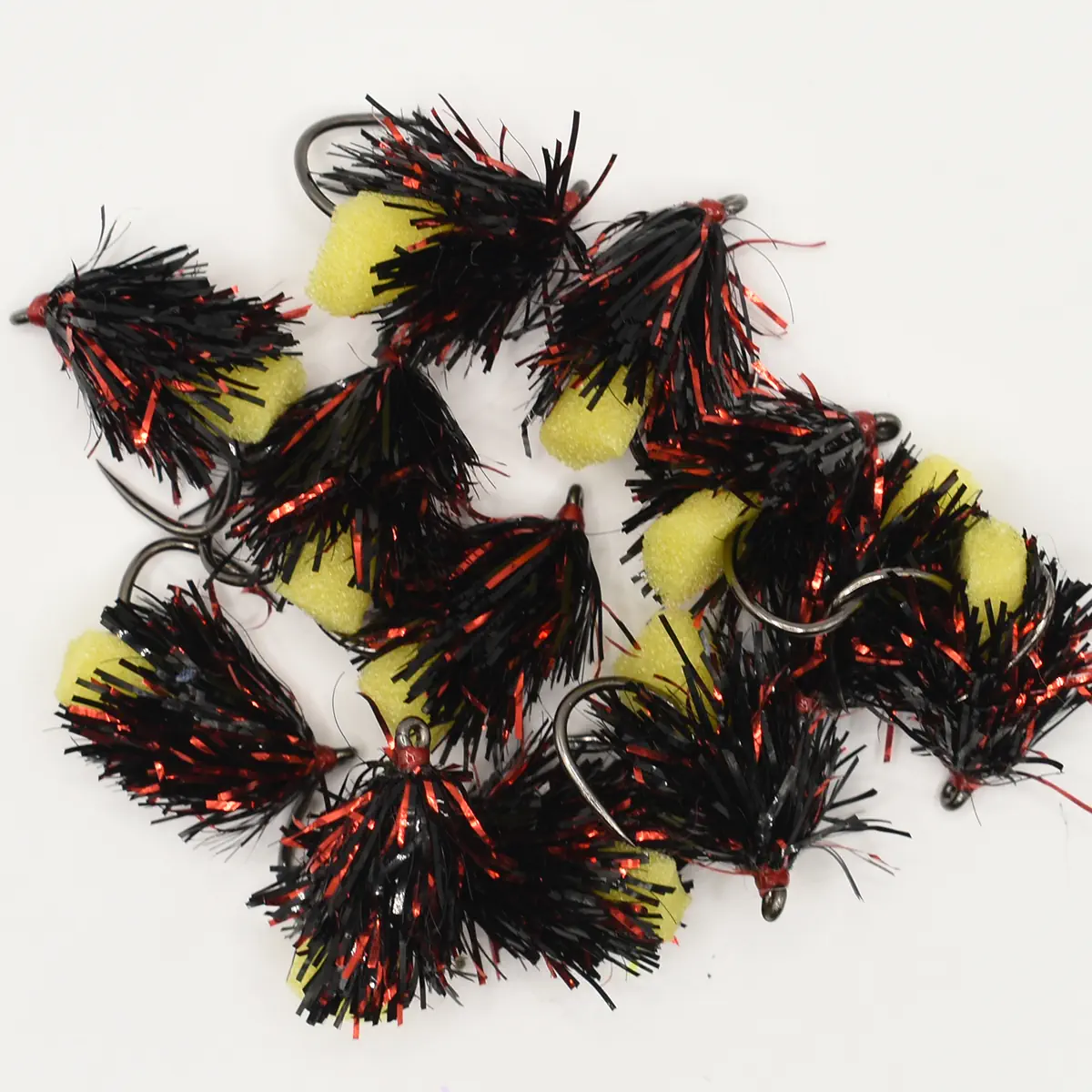 Close-up of black-and-red tinsel fishing lures with yellow foam beads and metal hooks
