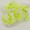 Assortment of neon yellow and white fishing flies with fluffy feather material and hooks visible.