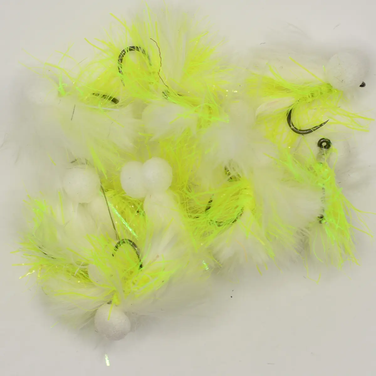 Assortment of neon yellow and white fishing flies with fluffy feather material and hooks visible.