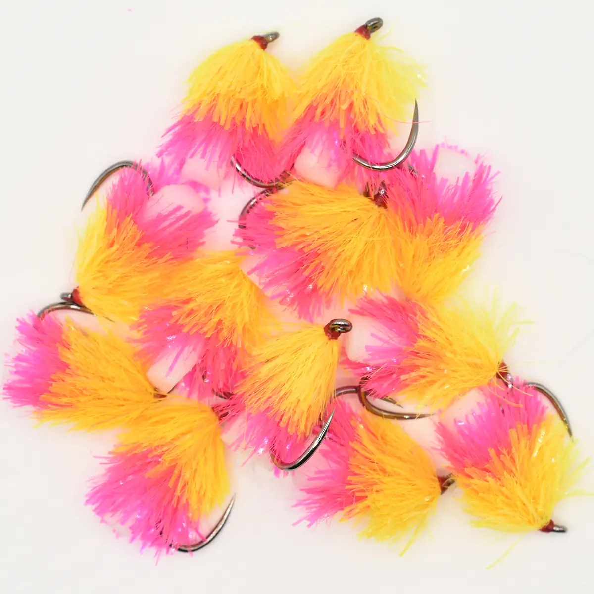 Assorted bright pink and yellow feather fishing lures with metal hooks on a white background