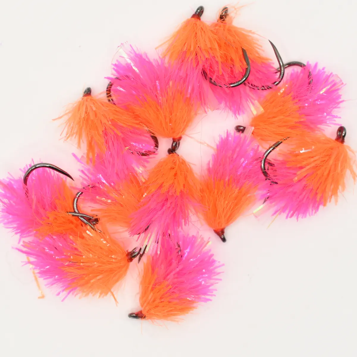 Bright pink and orange fluffy fishing lures with sharp hooks on a white background.