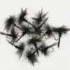 Collection of black dry fishing flies with feather hackles and hooks on a white background