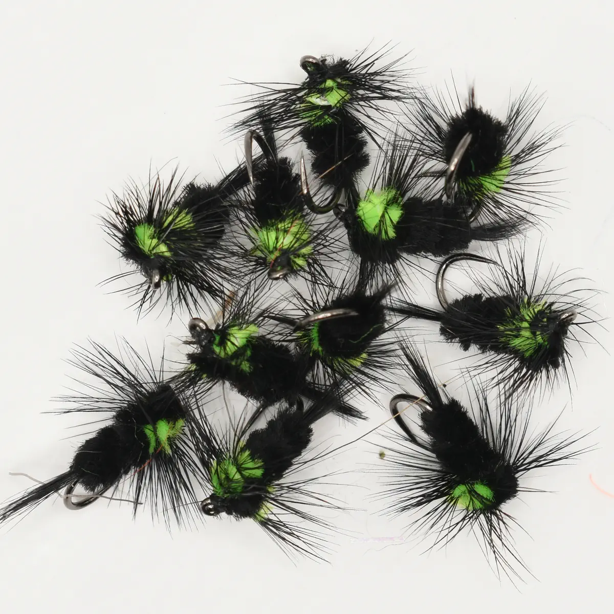Assorted black and neon green fishing flies with long black hackle feathers and hooks, arranged on a white background.