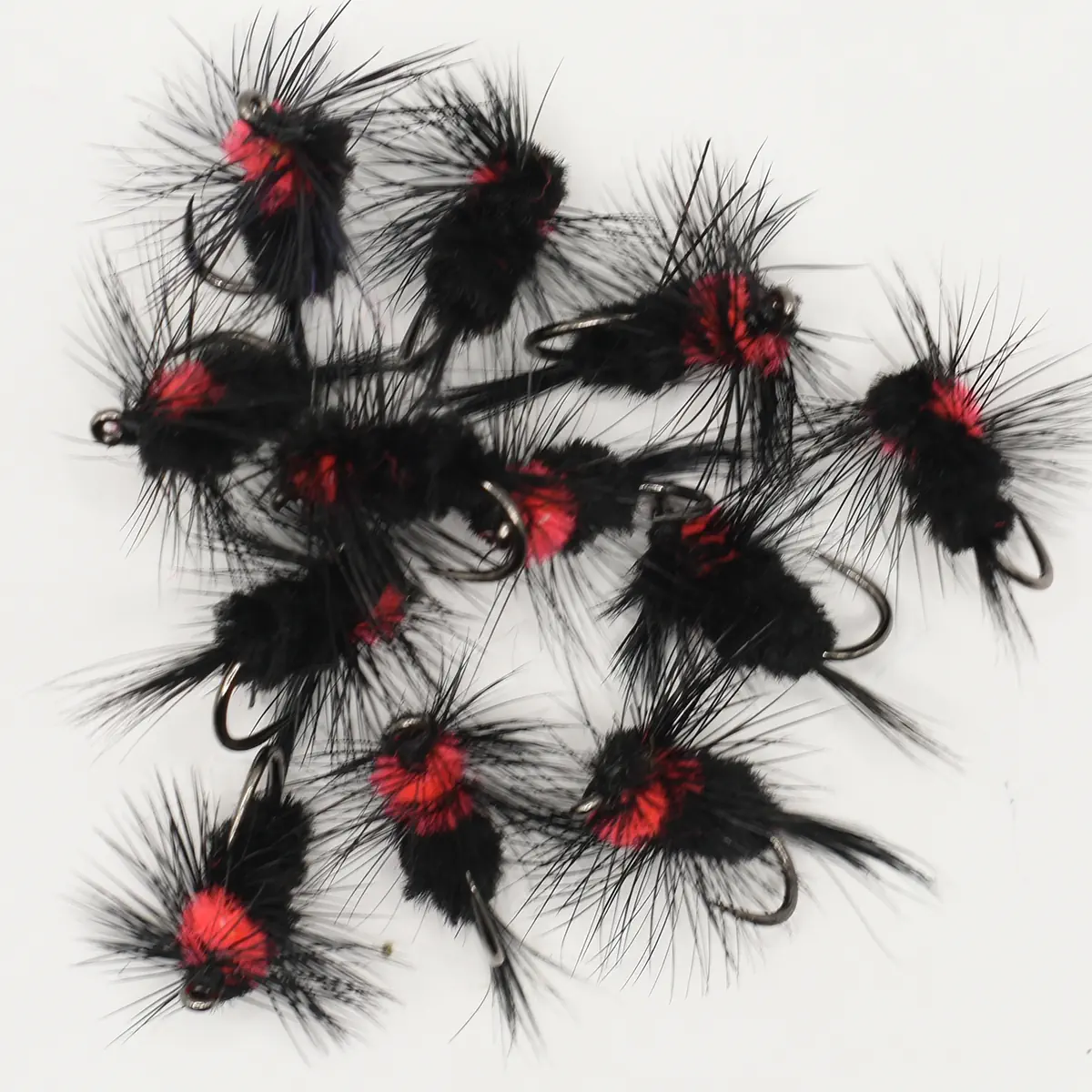 Assorted black and red fluffy fishing flies with hooks, arranged on a white background.