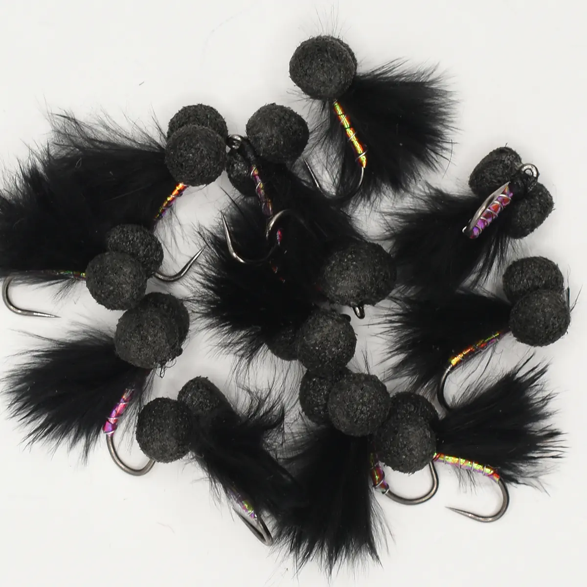 Assortment of black feather fishing lures with fuzzy pom-pom beads and sharp hooks.
