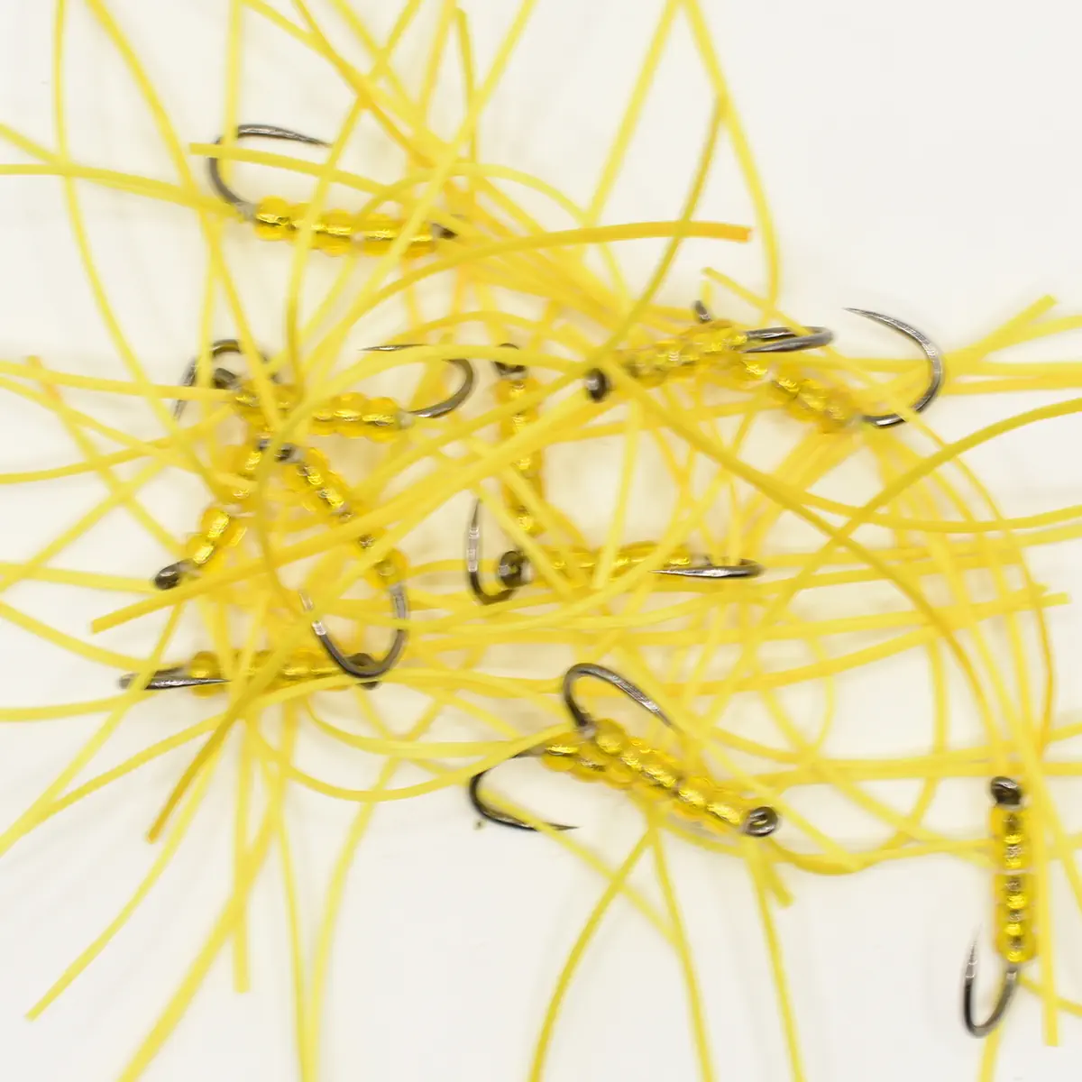 Pile of yellow soft-plastic fishing lures with hooks and beads scattered on a white surface, tangled together.