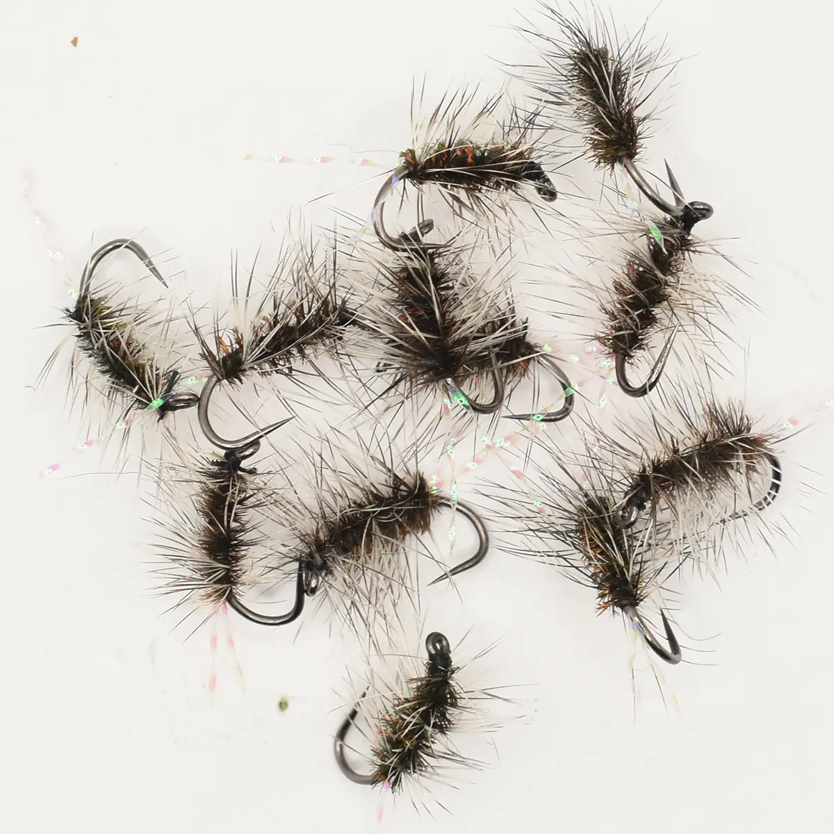 Assorted dark, fluffy fishing flies with long hackle and sharp hooks laid on a white surface.