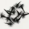 Several black fuzzy fishing flies with hooks arranged on a white background, used as lures for fly fishing