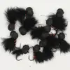 Black feathered fishing lures with fuzzy pom-poms and red thread, each with a sharp hook visible.