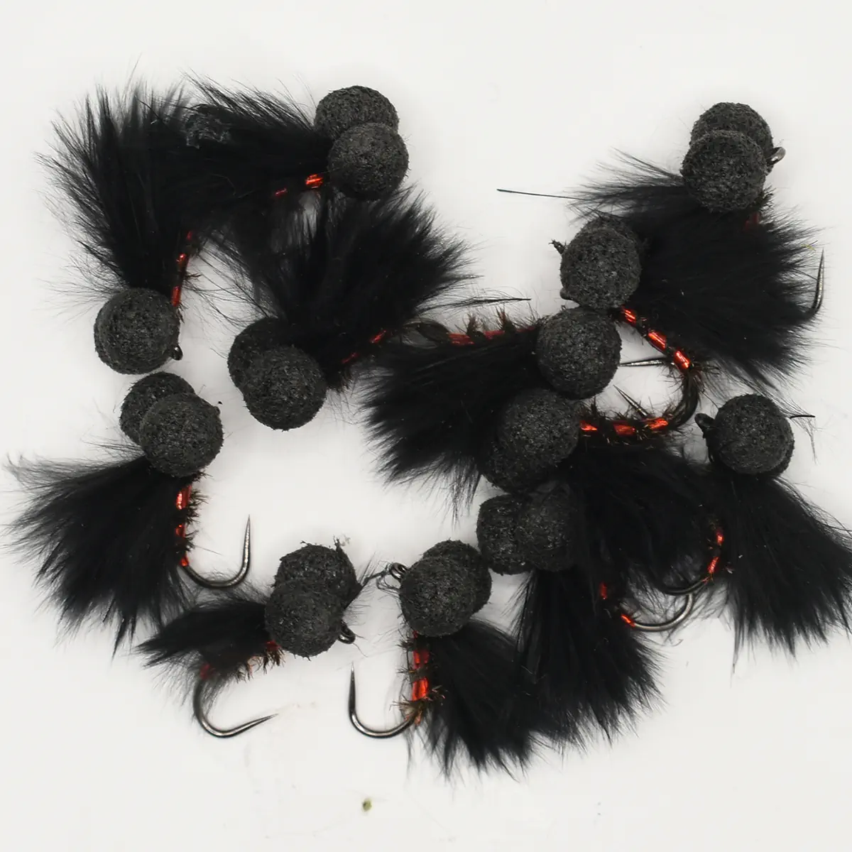 Black feathered fishing lures with fuzzy pom-poms and red thread, each with a sharp hook visible.