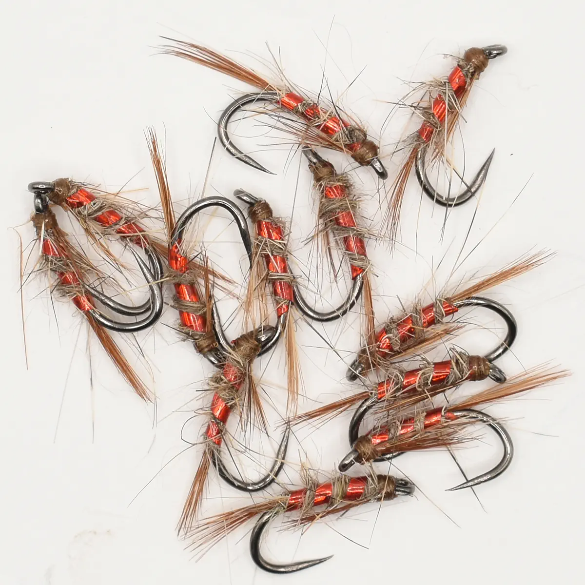 Assorted red-wrapped fishing flies with brown hackle scattered on a white background.