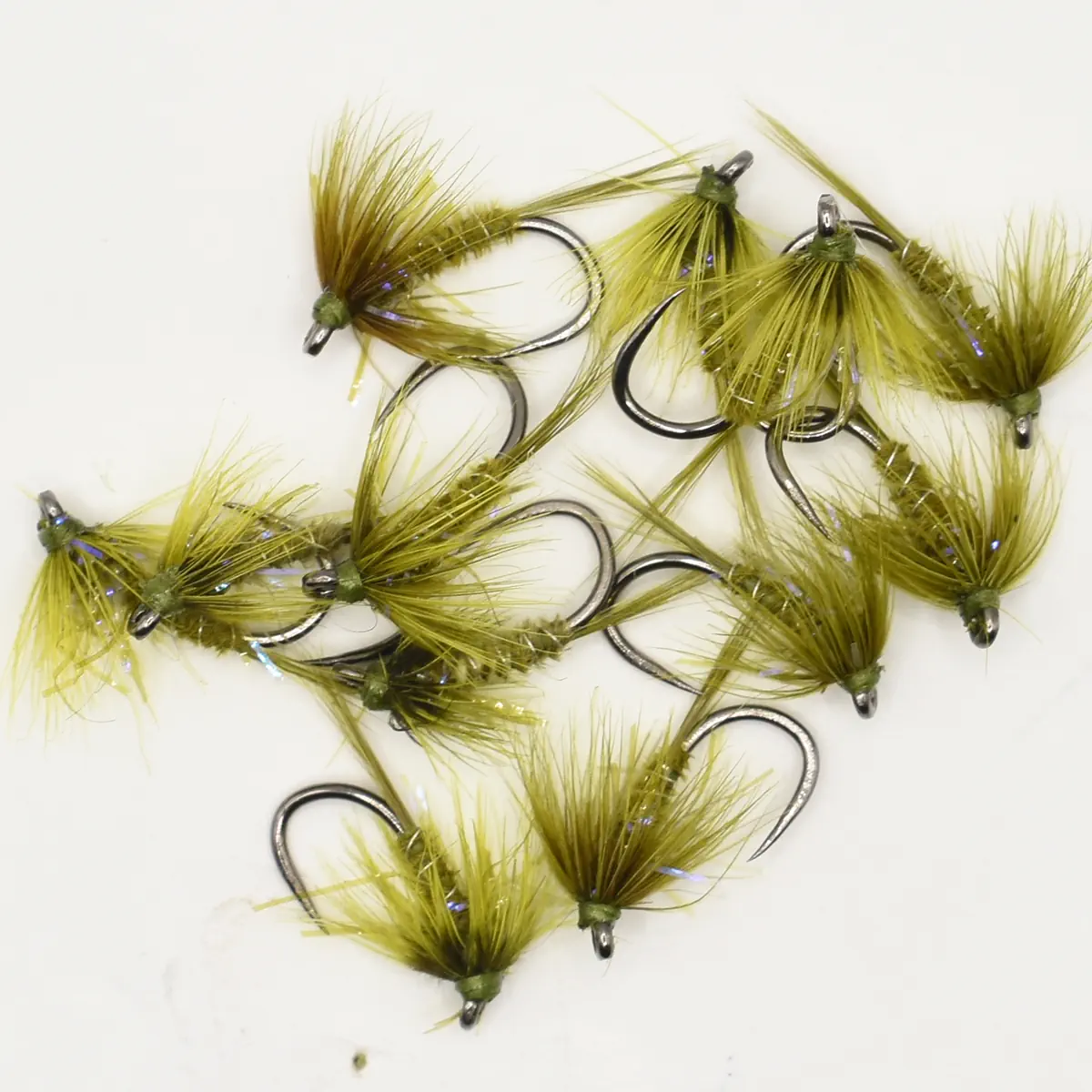 Several olive-green fishing flies with feathered hair attached to hooks on a white background, arranged loosely.