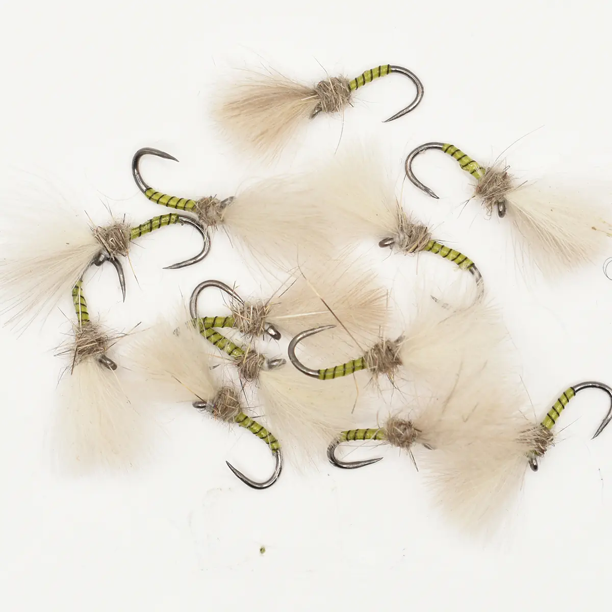 Assorted fly fishing lures with green striped bodies and fluffy tan tails scattered on a white background