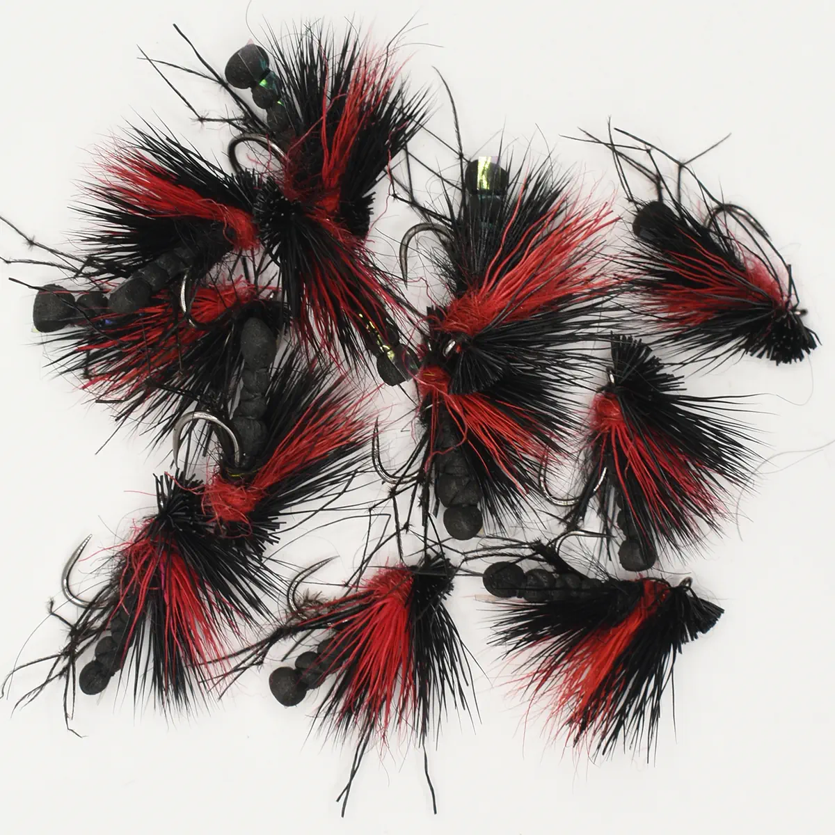 Assortment of black and red fuzzy fishing flies with hooks laid on a white background