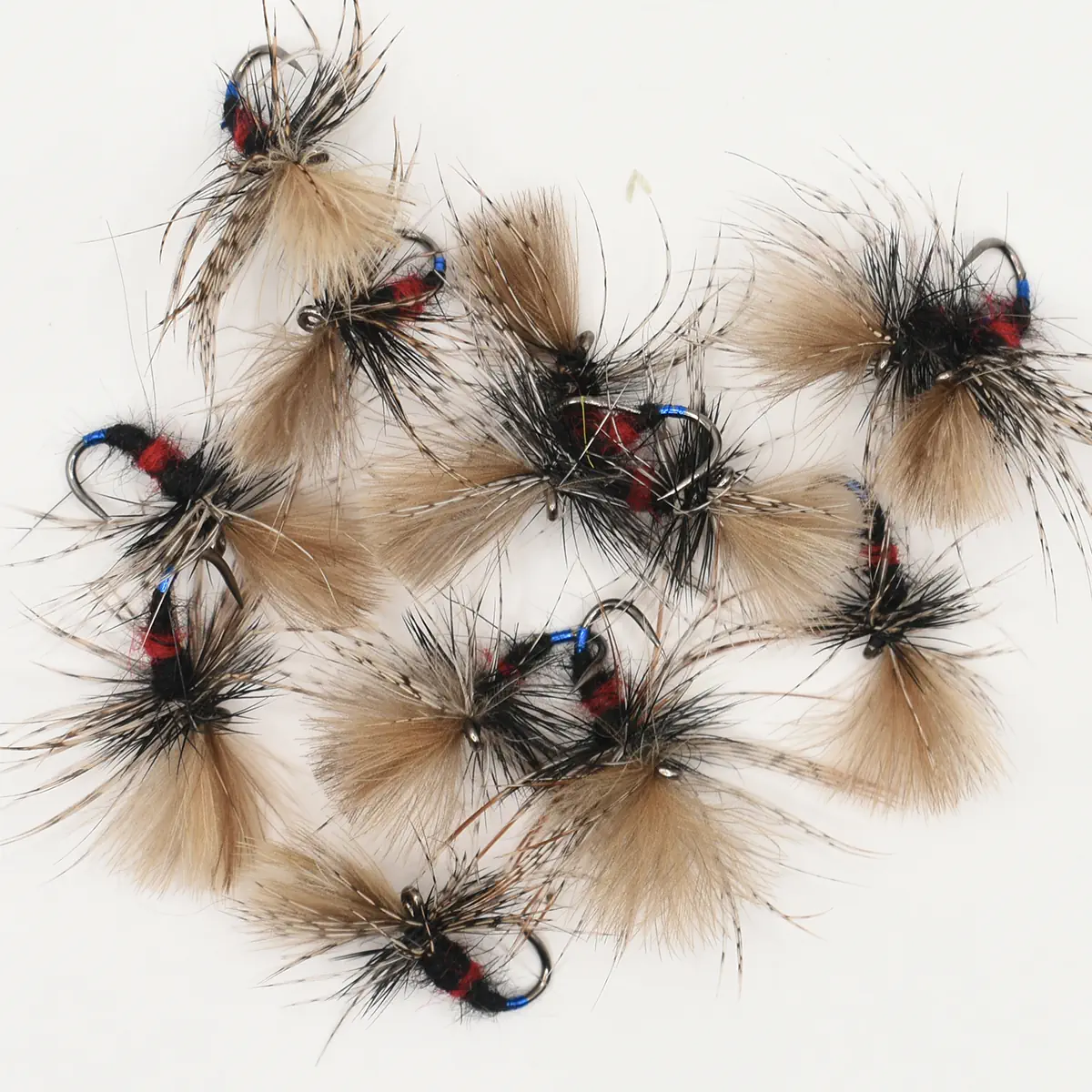 Assortment of fly fishing lures with tan and black fur on hooks, blue thread accents.