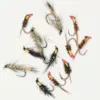 Assorted fly fishing flies laid out on a white surface, showing varied colors and types for tying or fishing.