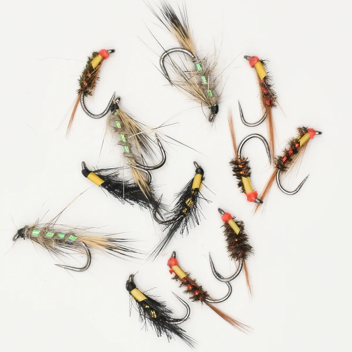 Assorted fly fishing flies laid out on a white surface, showing varied colors and types for tying or fishing.