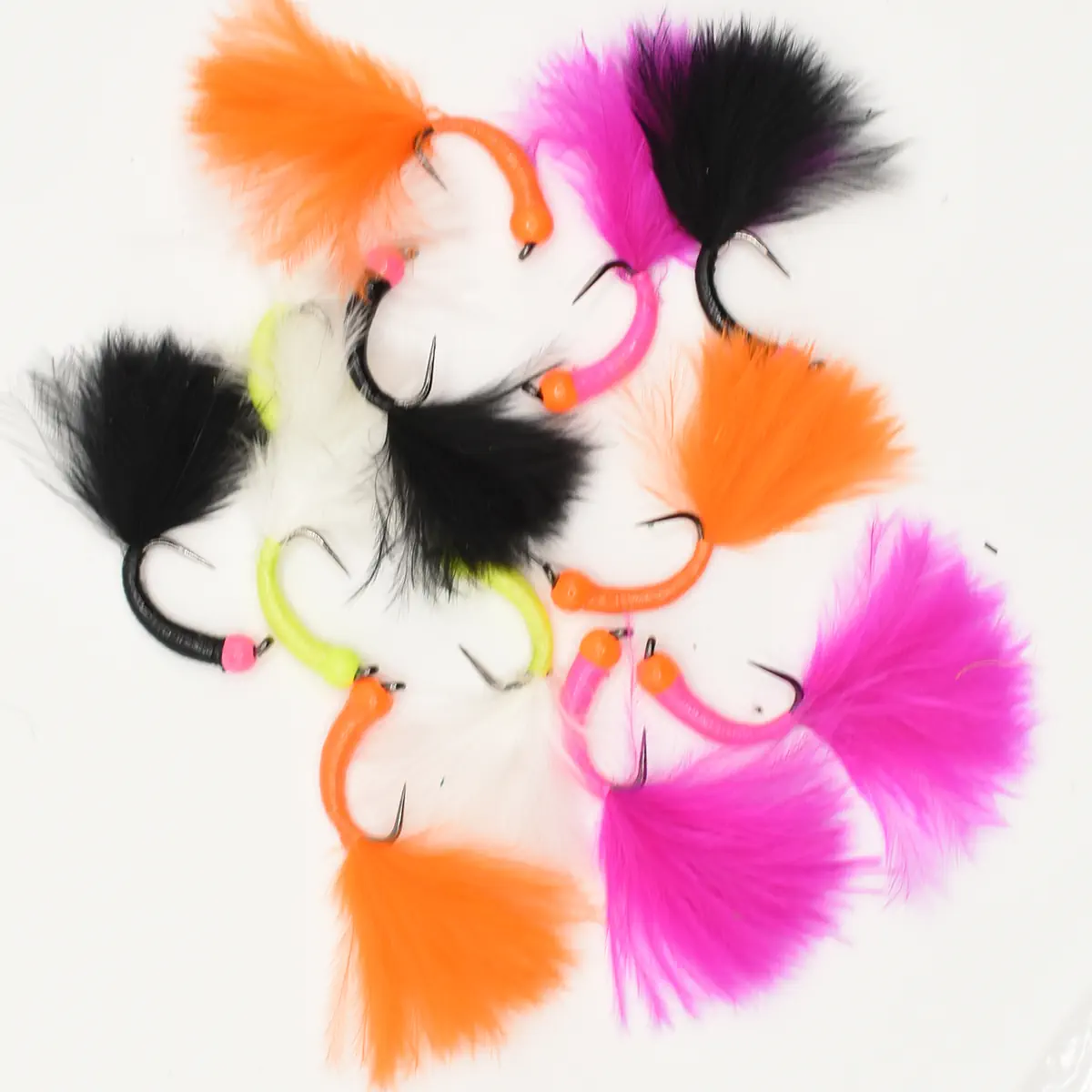 Assorted fishing flies with bright orange, pink, black feathers on metal hooks arranged in a circle.