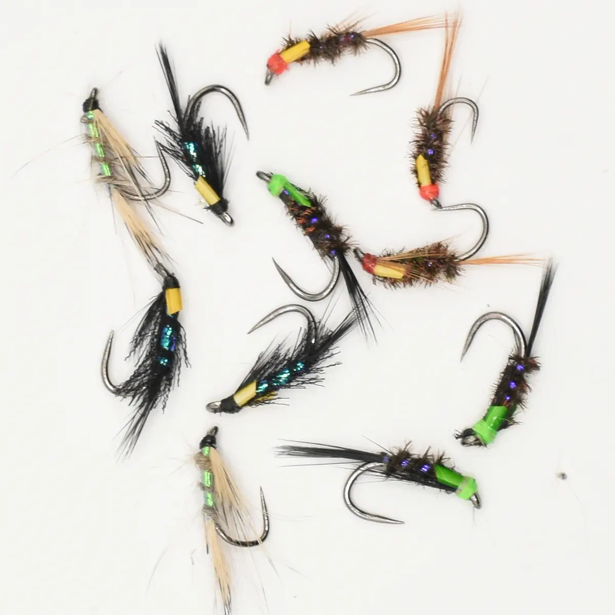 Assortment of colorful fishing flies with hooks for fly fishing on a white background.