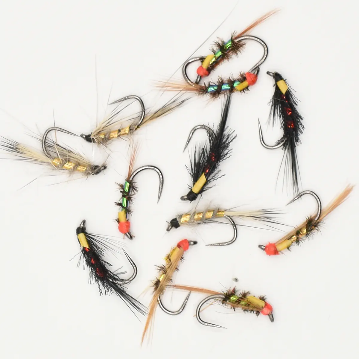 Assorted fishing flies arranged on a white background for fly fishing. Various colors and feathered bodies visible.